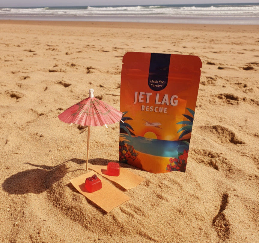 Packaged product labeled 'Jet Lag Rescue' on a sandy beach with a small umbrella and cookies.